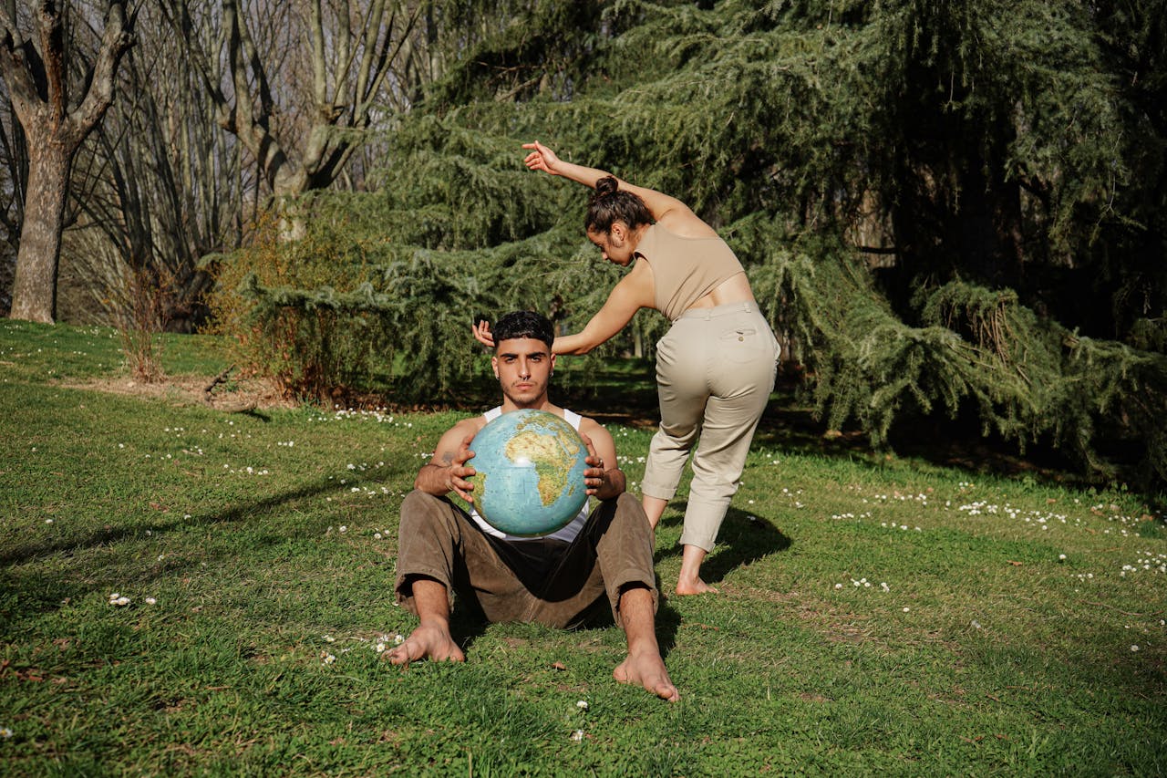 Two adults engaging in interpretive dance outdoors with a globe symbolizing unity and nature.